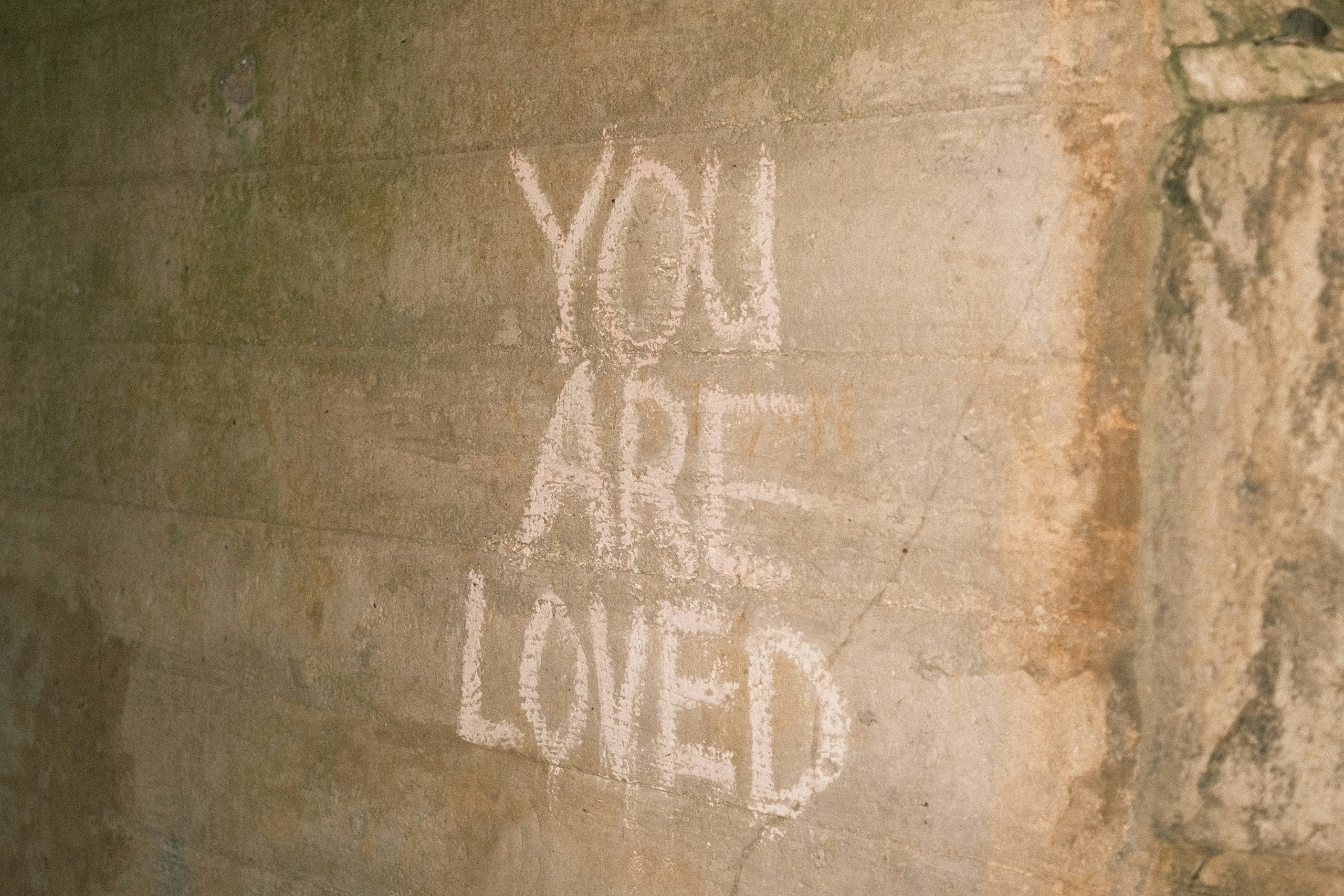 Stone block wall with the words "you are loved" written in chalk