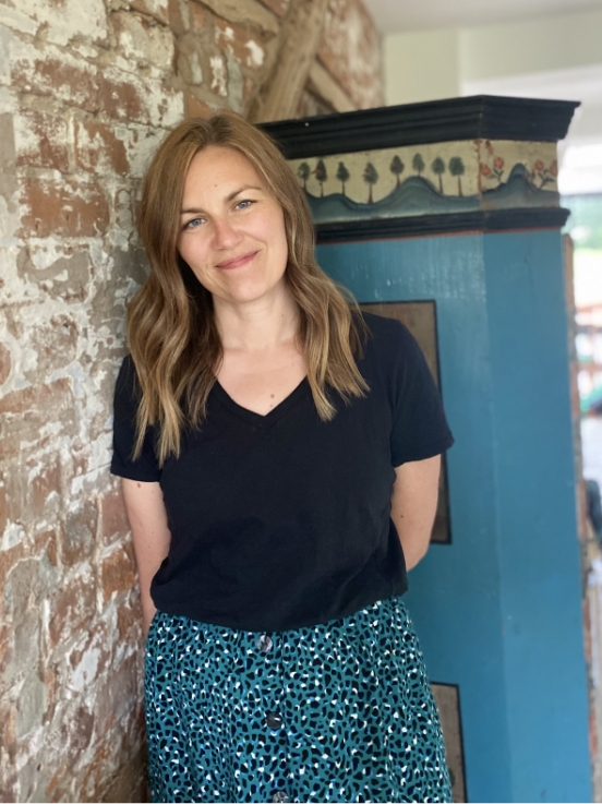 Lissy standing against a brown wall with a blie pillar behind her